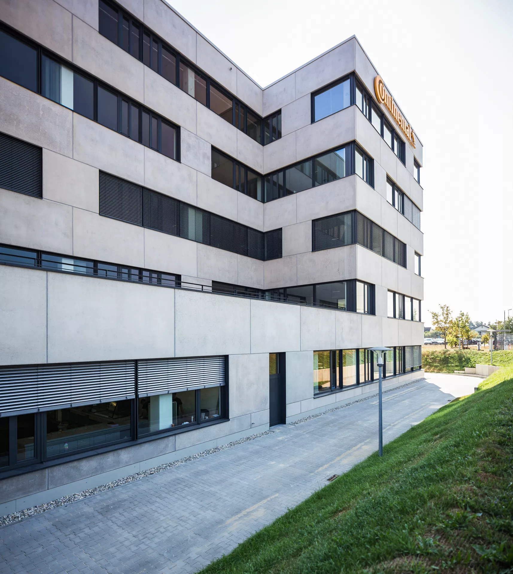 Modernes 5-stöckiges Gebäude polierter Betonfassade, breiten Fenstern, Terrasse im ersten Stock und "Continental"-Reklame an der Oberkante des Gebäudes. 