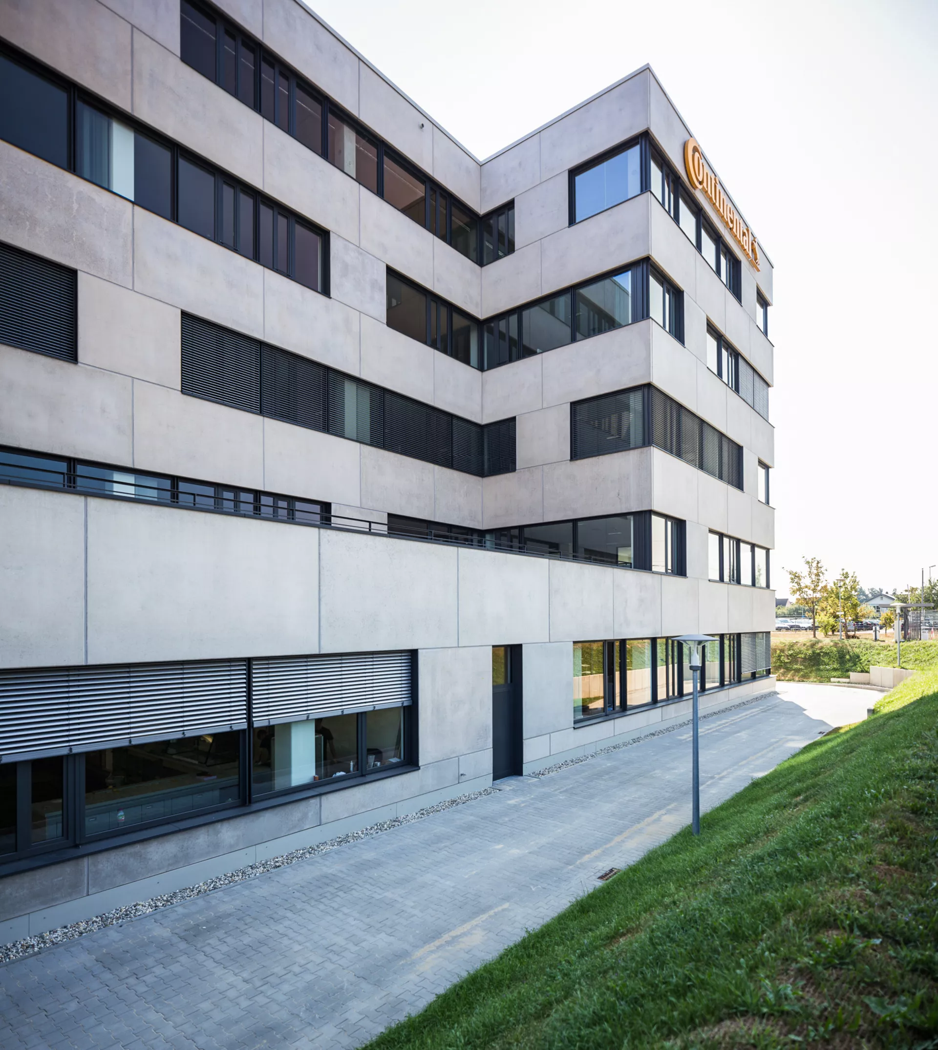 Modernes 5-stöckiges Gebäude polierter Betonfassade, breiten Fenstern, Terrasse im ersten Stock und "Continental"-Reklame an der Oberkante des Gebäudes. 