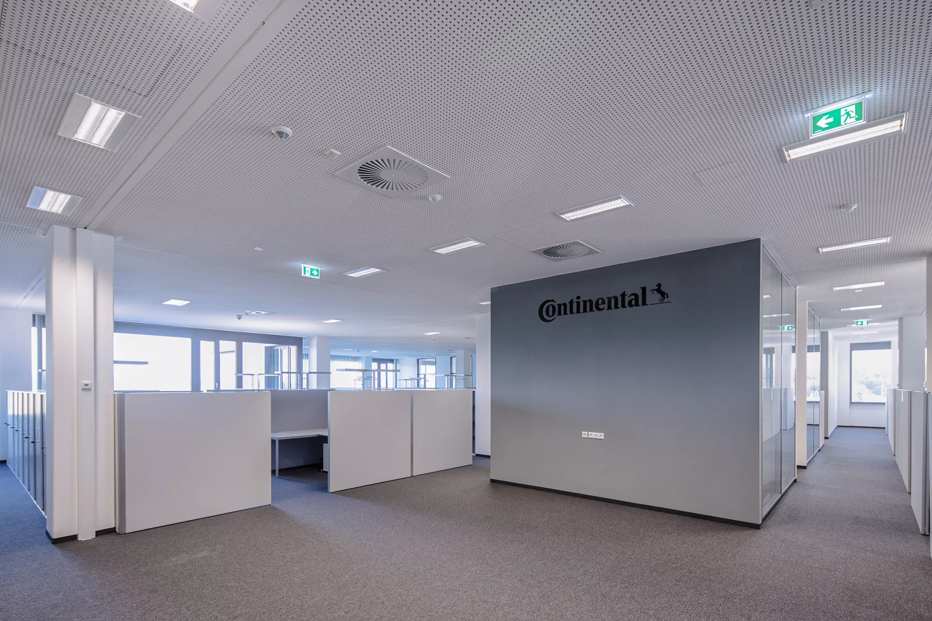 Großraumbüro mit grauem Teppichboden und Sitzwürfeln mit hellgrauen, brusthohen Wänden. Eine Wand grau mit schwarzem "Continental"-Schriftzug.